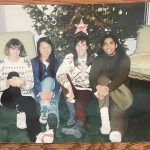 Four friends sitting on the floor in front of a Christmas tree
